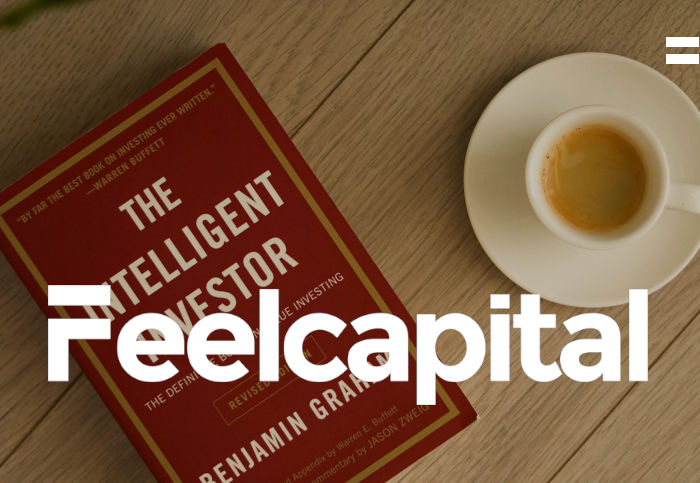 Mesa que tiene taza de café y el libro the intelligent investor